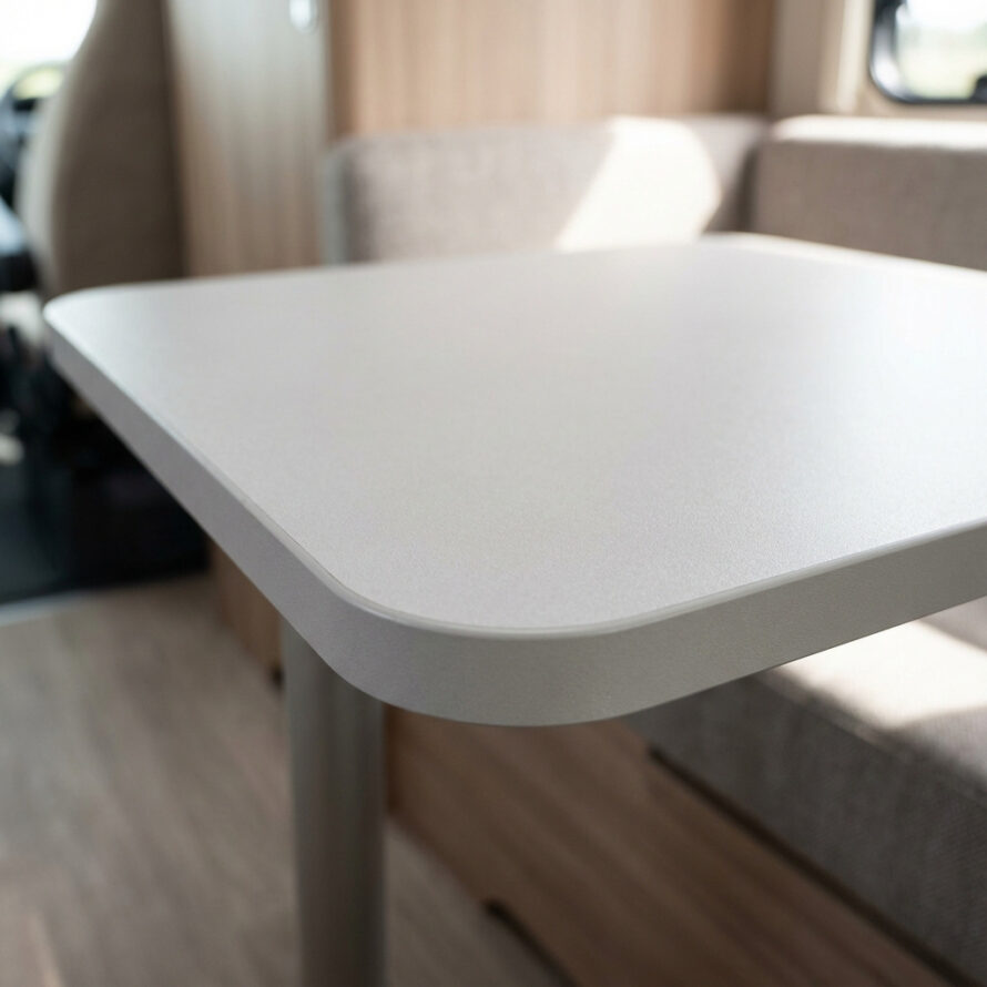 Close-up van een camper tafelblad met houtlook afwerking en afgeronde rand.