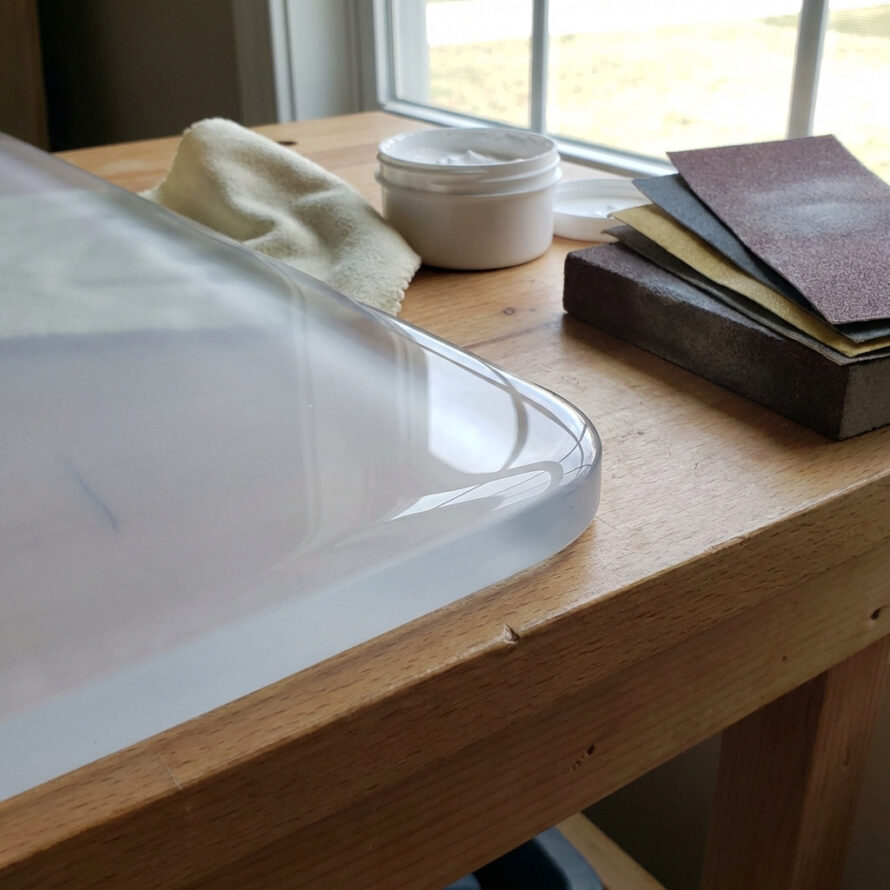 Plexiglas plaat met beschermfolie en gemarkeerde zaaglijn op houten werkblad.