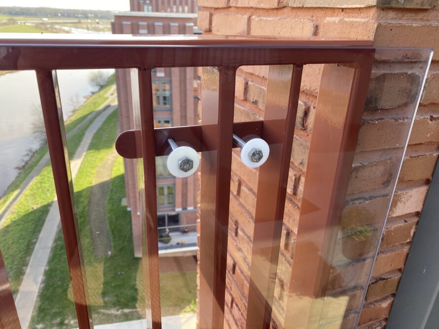 Detail van roestkleurige metalen spijlenrailing op een uitkijkplatform met uitzicht.