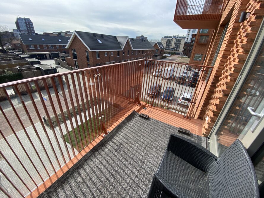 Trap en loopbrug van een uitkijktoren met roestkleurige metalen railing en uitzicht over het landschap.
