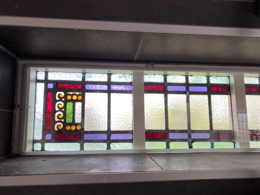 Breed glas-in-loodraam met rechthoekige kleuraccenten langs de randen.