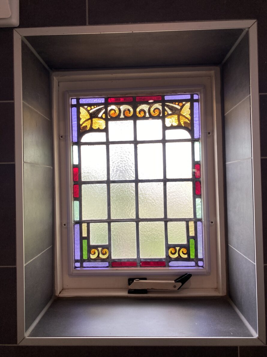 Smal glas-in-loodraam met kleurrijke decoratieve rand.