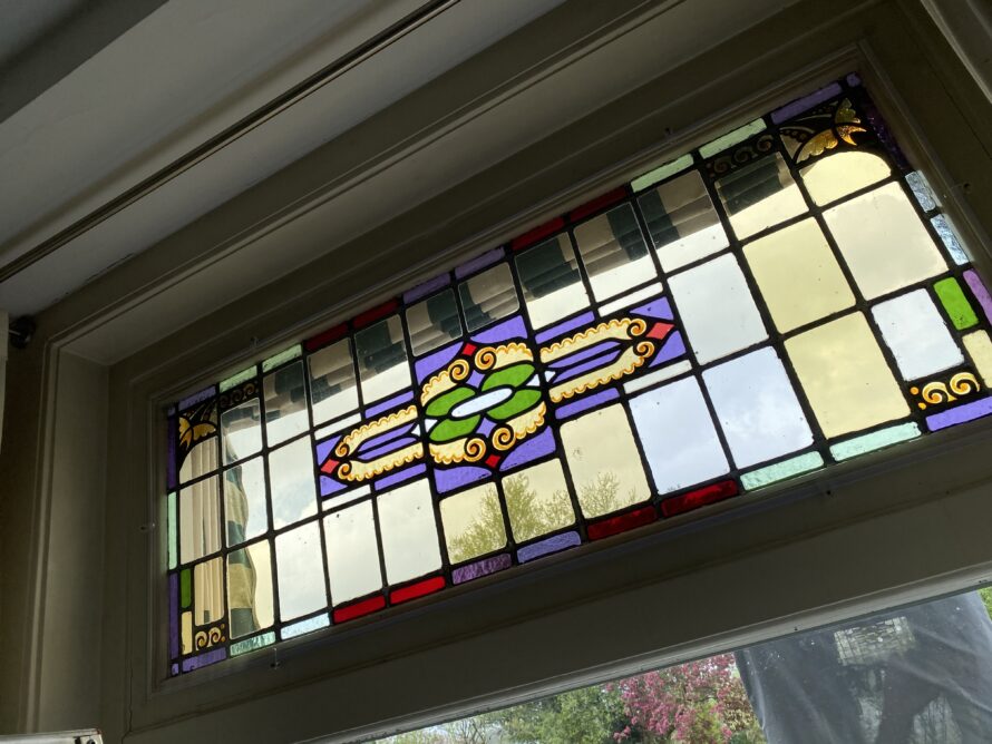 Gebogen glas-in-loodraam met kleurrijk geometrisch patroon.