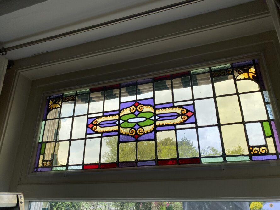 Gebogen glas-in-loodraam met centraal decoratief motief.