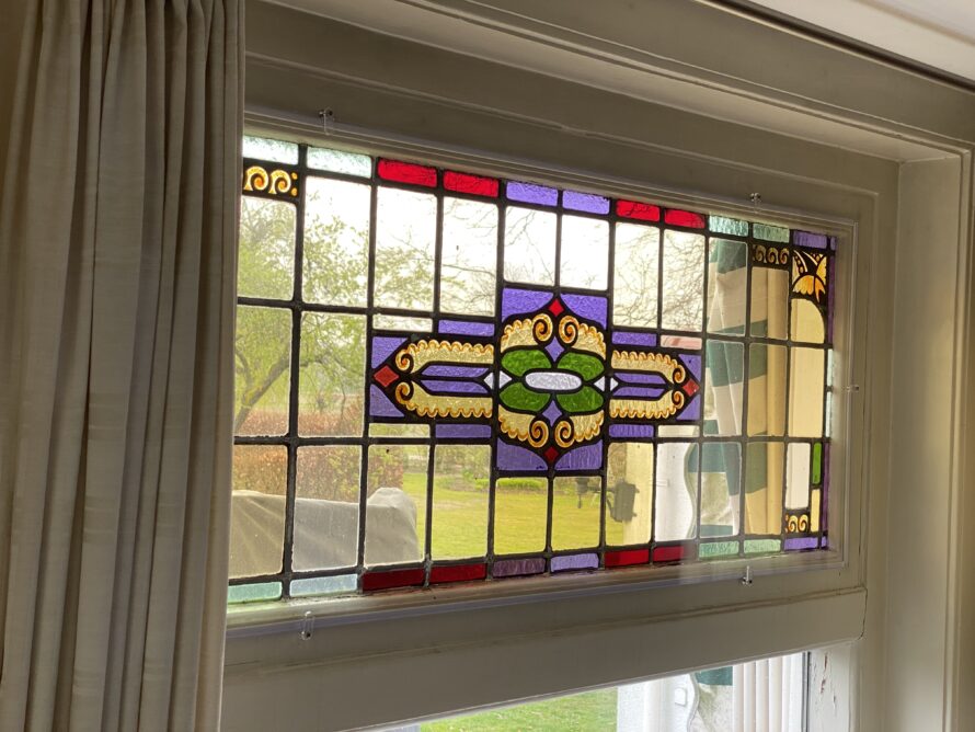 Glas-in-lood bovenraam met geometrisch en kleurrijk patroon.