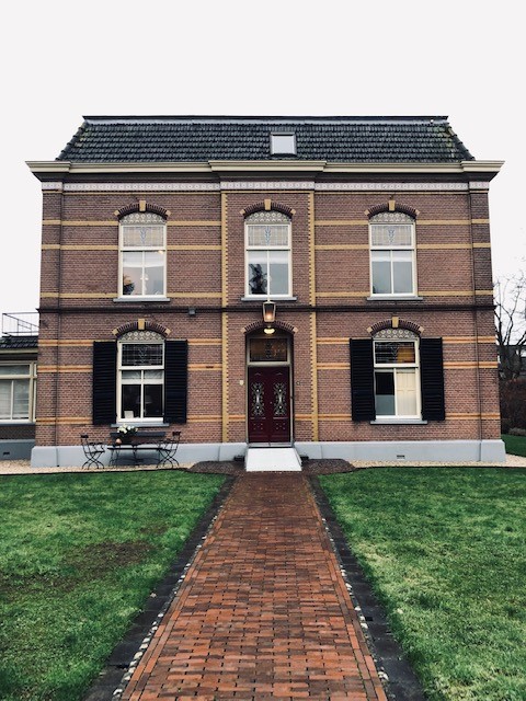 Symmetrische bakstenen woning met klassieke ramen en luiken.