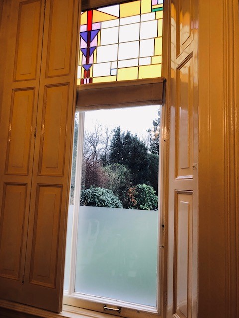 Houten deur met glas-in-loodraam en uitzicht op een tuin.