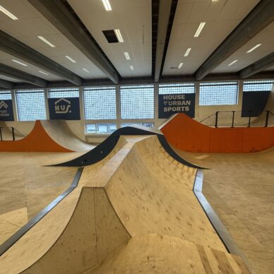 Binnenruimte met meerdere houten ramps en bowls, inclusief een centrale kom en omliggende platforms.