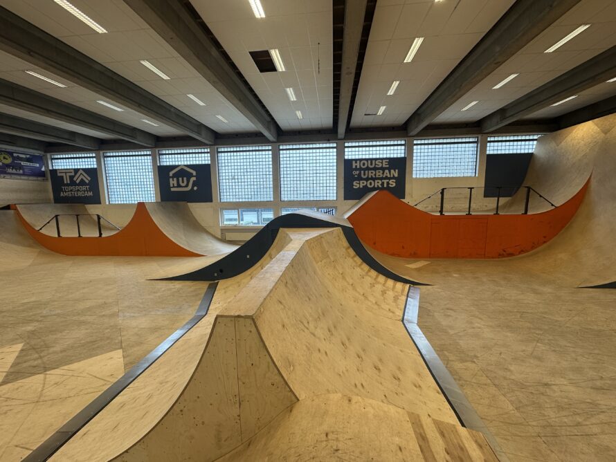 Binnenruimte met meerdere houten ramps en bowls, inclusief een centrale kom en omliggende platforms.